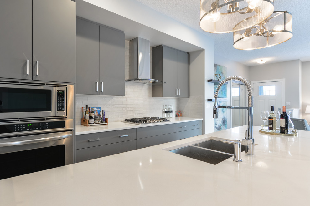 Inspiration for a mid-sized contemporary galley eat-in kitchen in Edmonton with an undermount sink, flat-panel cabinets, grey cabinets, quartzite benchtops, white splashback, ceramic splashback, stainless steel appliances, vinyl floors, with island, white floor and white benchtop.