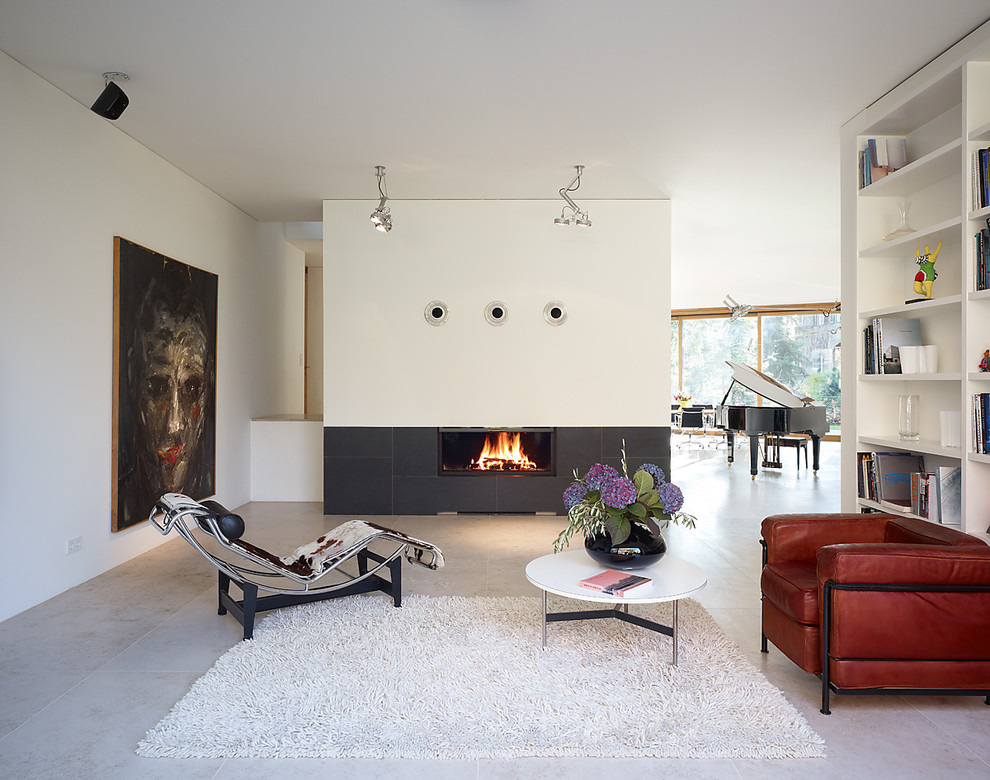 Large modern open concept family room in Berlin with a library, white walls, a standard fireplace, a metal fireplace surround and grey floor.