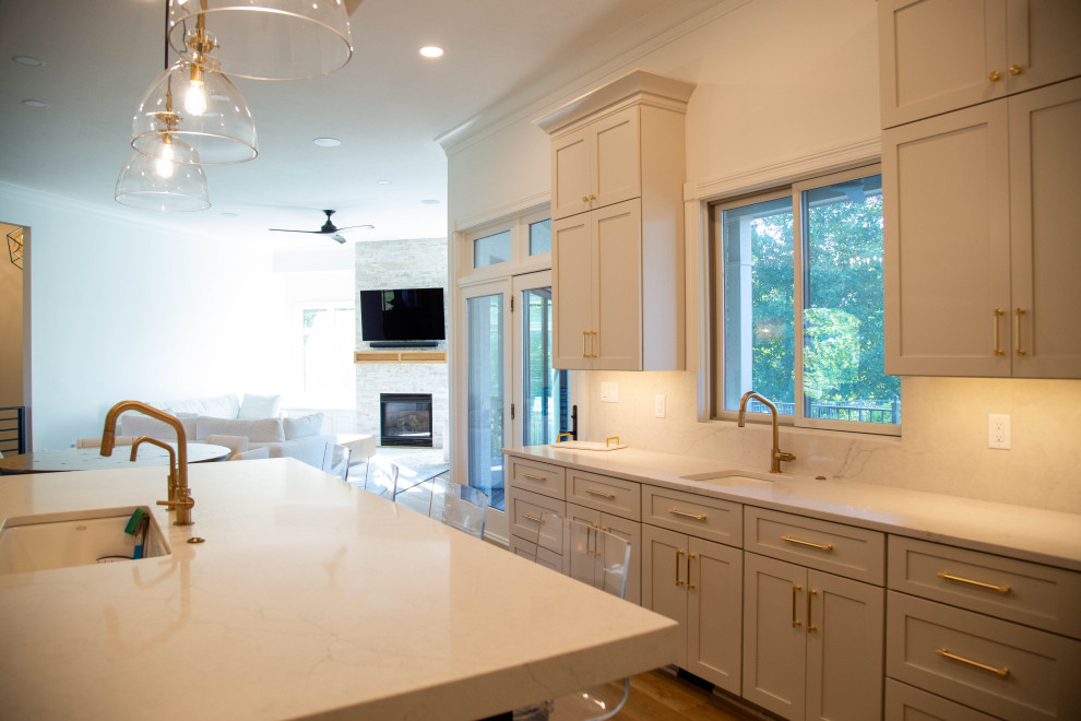 This is an example of a large transitional u-shaped eat-in kitchen in Indianapolis with an undermount sink, shaker cabinets, white cabinets, quartz benchtops, white splashback, engineered quartz splashback, stainless steel appliances, laminate floors, with island, blue floor, white benchtop and exposed beam.