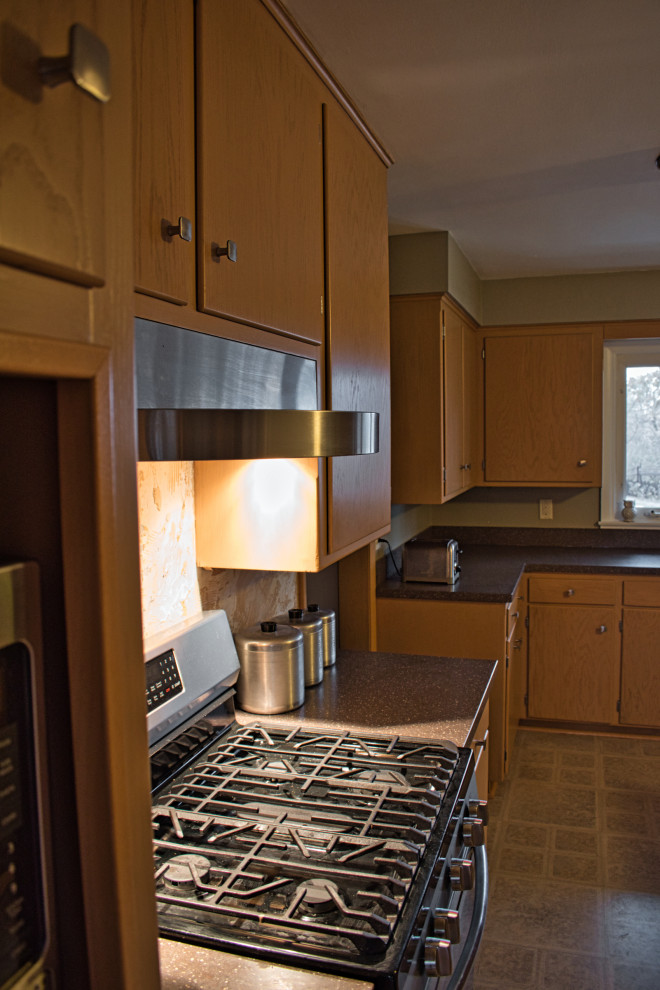 Photo of a large midcentury l-shaped separate kitchen in Other with flat-panel cabinets, light wood cabinets, solid surface benchtops, grey splashback, stainless steel appliances, with island and grey benchtop.