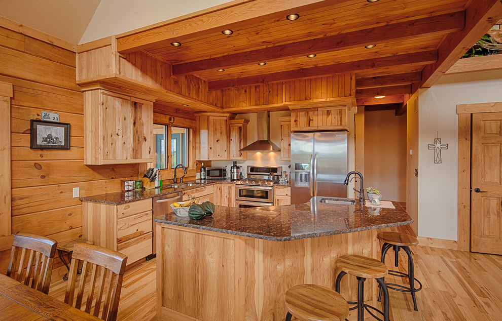 Mid-sized country l-shaped open plan kitchen in Denver with an undermount sink, flat-panel cabinets, brown cabinets, granite benchtops, timber splashback, stainless steel appliances, light hardwood floors, with island and brown floor.