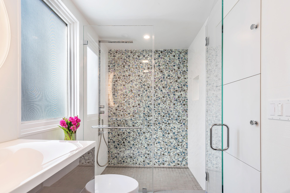 Inspiration for a small contemporary 3/4 bathroom in San Francisco with flat-panel cabinets, brown cabinets, an alcove shower, a one-piece toilet, multi-coloured tile, glass tile, white walls, porcelain floors, an integrated sink, glass benchtops, grey floor, a hinged shower door and white benchtops.