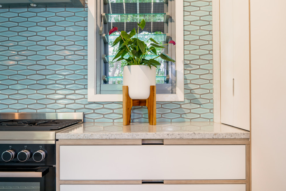 Bild på ett mellanstort 50 tals flerfärgad flerfärgat u-kök, med släta luckor, vita skåp, laminatbänkskiva, blått stänkskydd, svarta vitvaror och en köksö