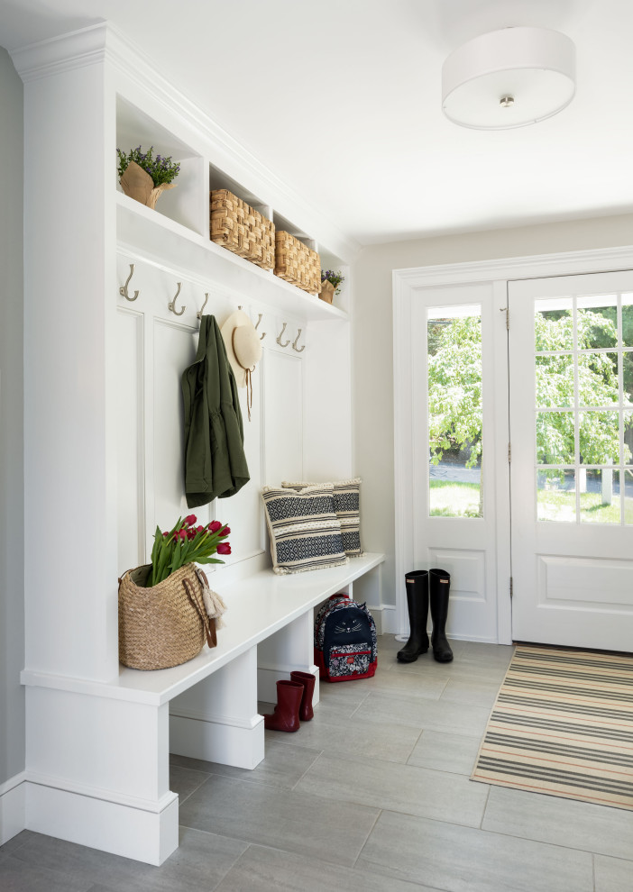 This is an example of a traditional mudroom in Boston with white walls, ceramic floors, a single front door and grey floor.