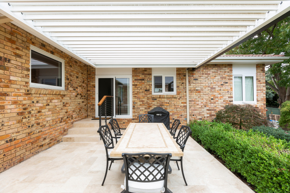 Idées déco pour une terrasse arrière classique de taille moyenne avec des pavés en pierre naturelle et une extension de toiture.