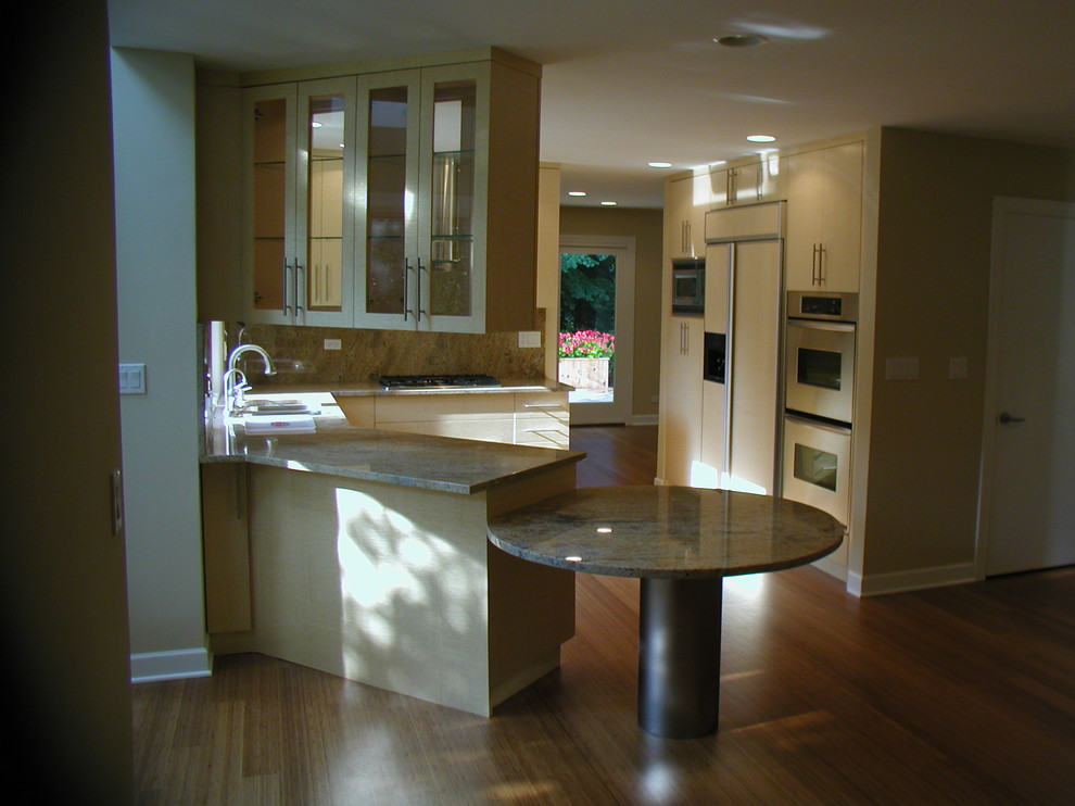 This is an example of a mid-sized transitional u-shaped eat-in kitchen in Chicago with a double-bowl sink, flat-panel cabinets, white cabinets, granite benchtops, beige splashback, stone slab splashback, stainless steel appliances, medium hardwood floors and no island.
