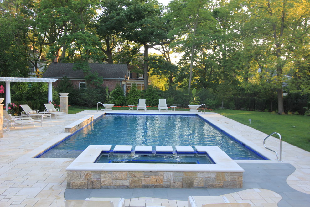 Photo of a large traditional backyard rectangular lap pool in Chicago with a hot tub and concrete pavers.