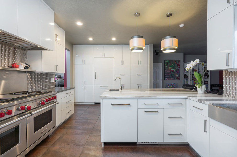 Kitchen - contemporary porcelain tile and brown floor kitchen idea with flat-panel cabinets, white cabinets, gray backsplash, stainless steel appliances and an island