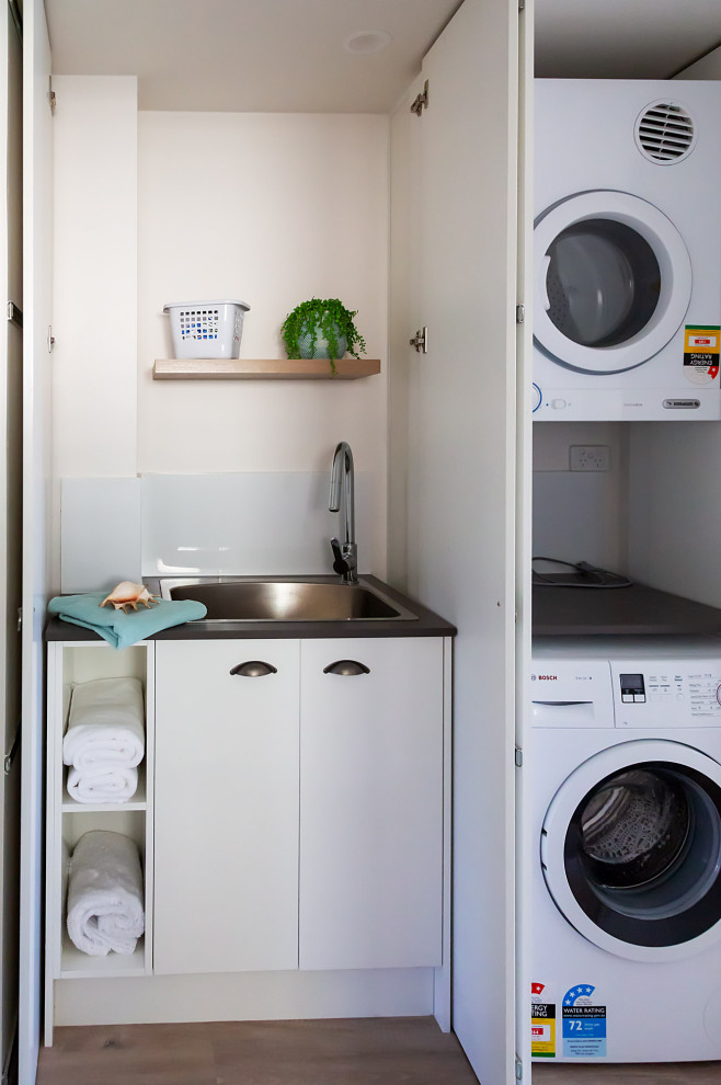 Foto di una lavanderia minimalista con lavello da incasso, top in laminato e lavatrice e asciugatrice a colonna