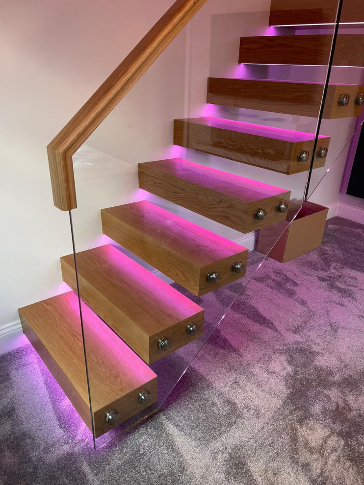 Inspiration for a small contemporary wood straight glass railing staircase in Manchester with open risers and feature lighting.