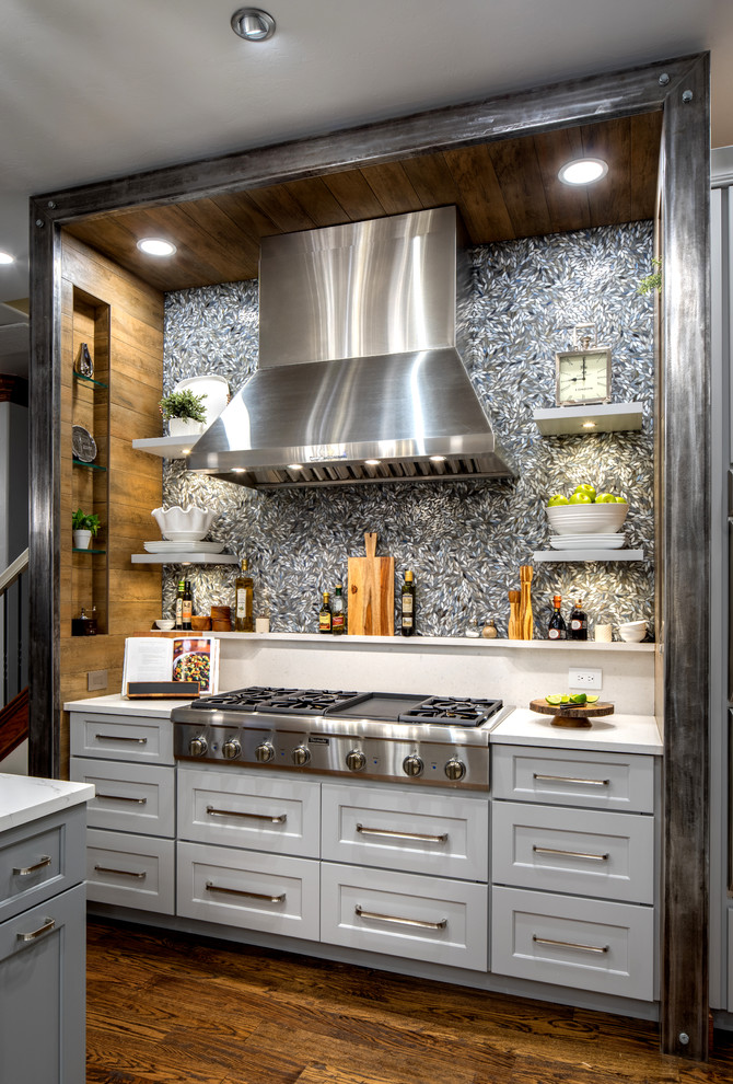 This is an example of a large transitional open plan kitchen in Oklahoma City with a single-bowl sink, shaker cabinets, grey cabinets, quartz benchtops, grey splashback, porcelain splashback, stainless steel appliances, medium hardwood floors, with island and brown floor.