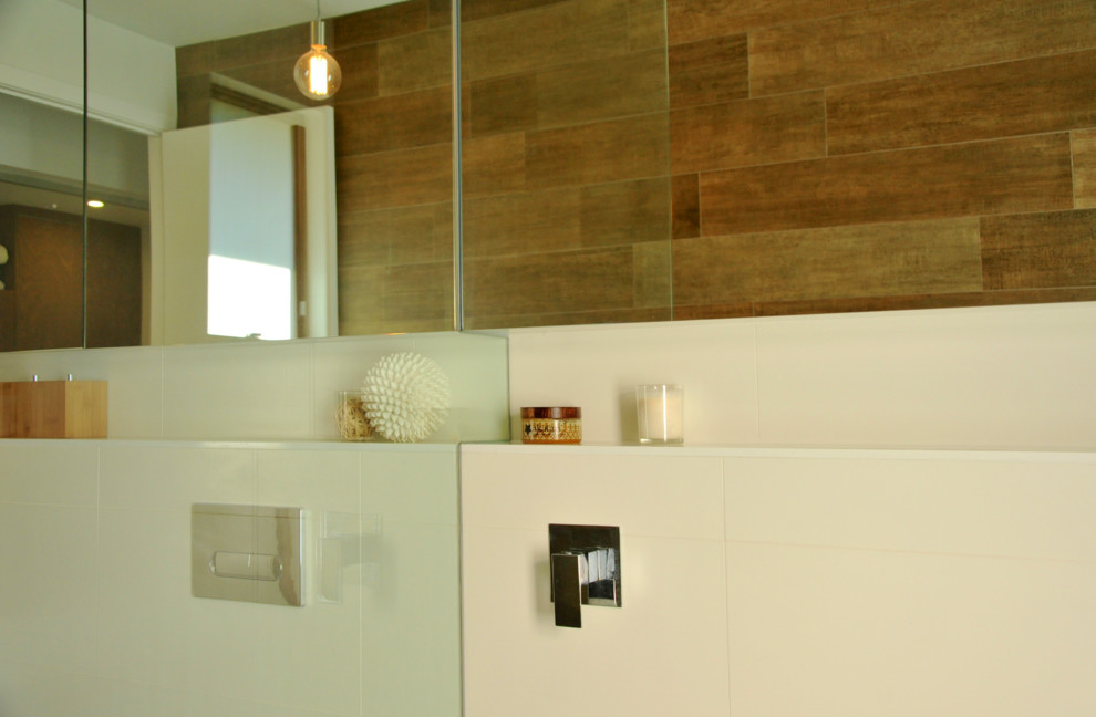Contemporary bathroom in Brisbane with a wall-mount sink, glass-front cabinets, white cabinets, a freestanding tub, an open shower and a wall-mount toilet.