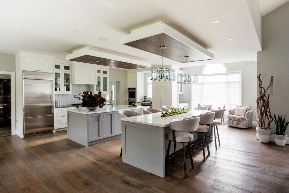 Eat-in kitchen - transitional l-shaped dark wood floor and brown floor eat-in kitchen idea in Toronto with shaker cabinets, gray cabinets, gray backsplash, stainless steel appliances, two islands and white countertops