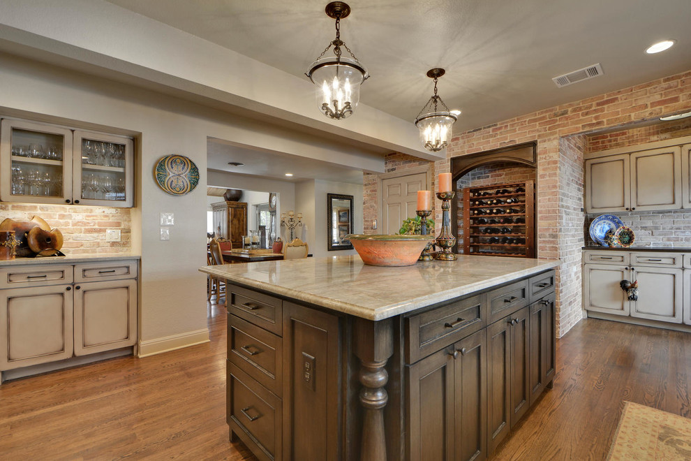 Large traditional u-shaped eat-in kitchen in Austin with a farmhouse sink, shaker cabinets, beige cabinets, solid surface benchtops, beige splashback, stone tile splashback, stainless steel appliances, medium hardwood floors and with island.
