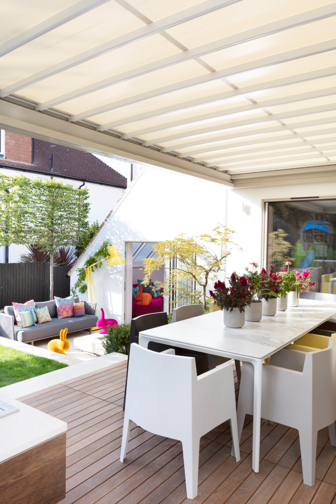 Inspiration for an eclectic backyard patio in London with decking and an awning.