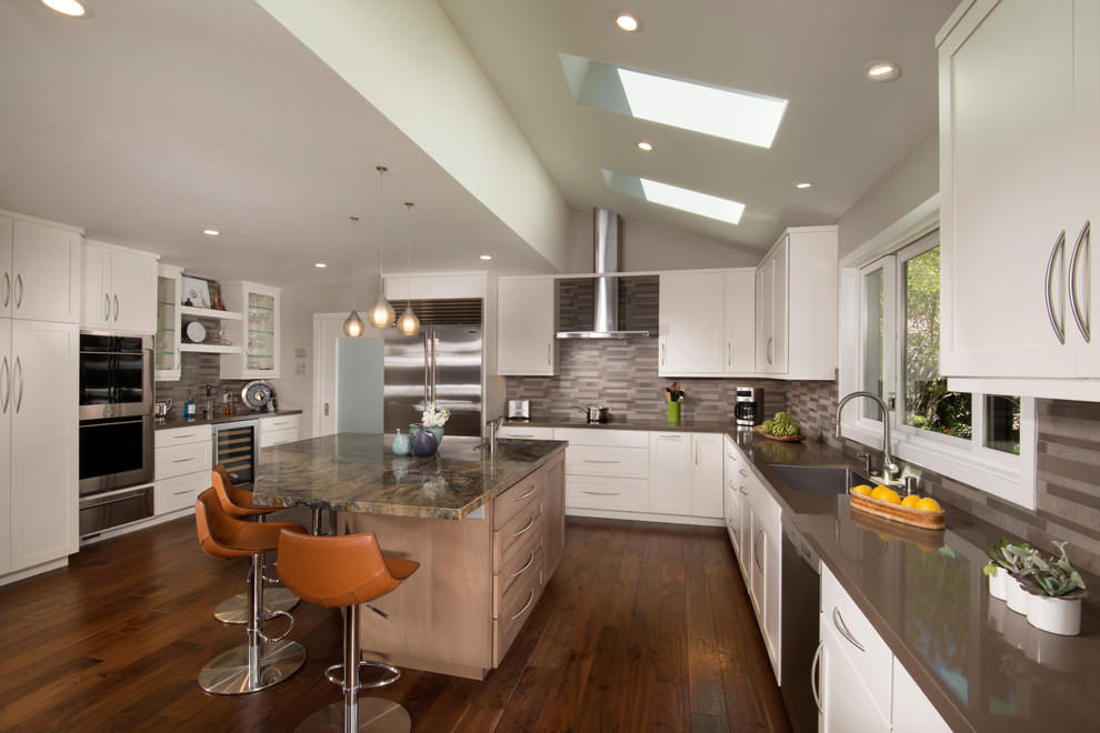 Inspiration for an expansive transitional l-shaped eat-in kitchen in San Francisco with a single-bowl sink, shaker cabinets, matchstick tile splashback, stainless steel appliances, medium hardwood floors, with island, grey benchtop, white cabinets, quartz benchtops, brown splashback, brown floor and vaulted.