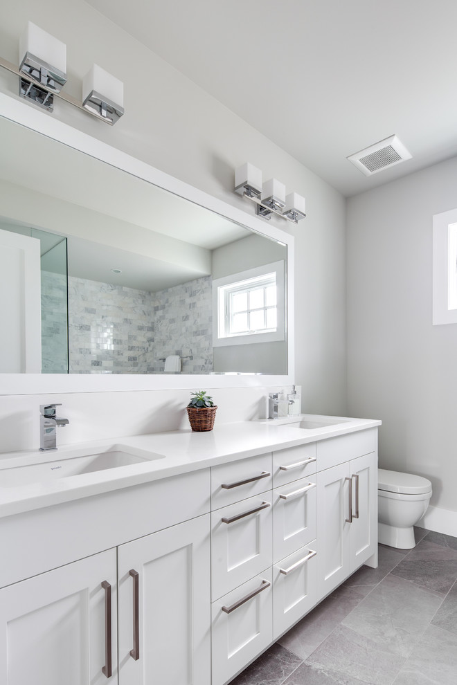 Mid-sized transitional master bathroom in Vancouver with shaker cabinets, white cabinets, a drop-in tub, a corner shower, a two-piece toilet, gray tile, marble, grey walls, porcelain floors, an undermount sink, engineered quartz benchtops, grey floor, a hinged shower door and white benchtops.