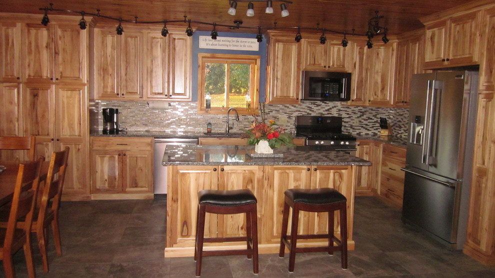 Mid-sized mountain style l-shaped porcelain tile and gray floor eat-in kitchen photo with a double-bowl sink, raised-panel cabinets, light wood cabinets, granite countertops, multicolored backsplash, matchstick tile backsplash, stainless steel appliances and an island
