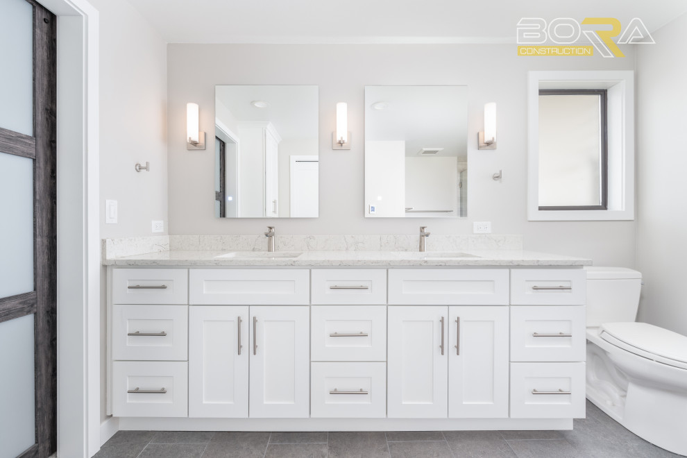 Design ideas for a large transitional master bathroom in Seattle with shaker cabinets, white cabinets, an alcove shower, a two-piece toilet, white tile, white walls, ceramic floors, an undermount sink, engineered quartz benchtops, grey floor, a hinged shower door, white benchtops, a double vanity and a built-in vanity.