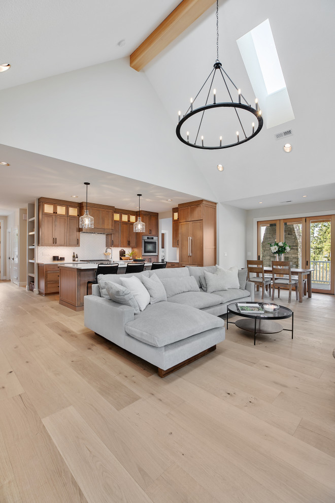 Design ideas for an expansive traditional open plan living room in Portland with a home bar, grey walls, light hardwood flooring, a wood burning stove, a stacked stone fireplace surround, no tv, brown floors and a vaulted ceiling.