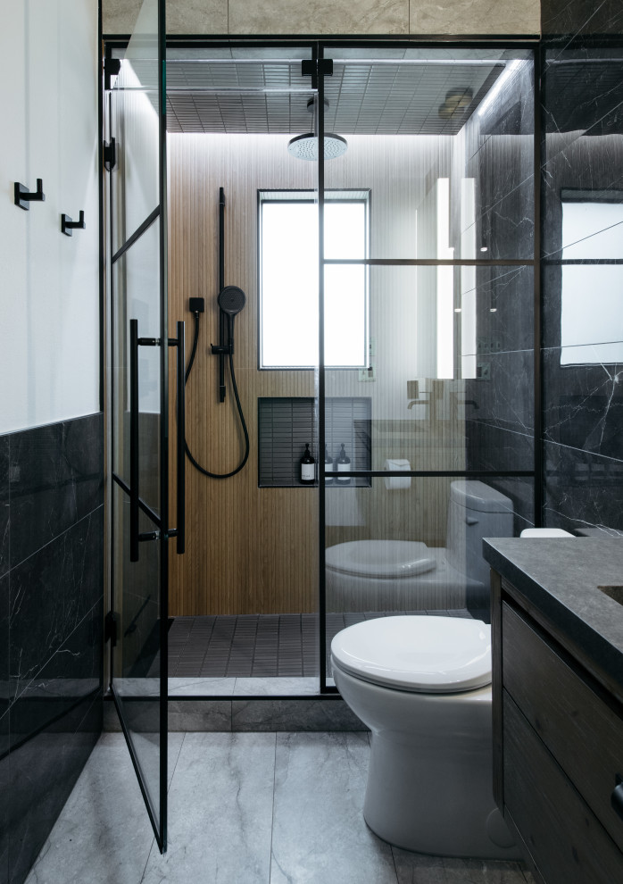 Design ideas for a contemporary 3/4 bathroom in Houston with flat-panel cabinets, an alcove shower, black tile, an integrated sink, grey floor, a hinged shower door, grey benchtops, a single vanity, a floating vanity and medium wood cabinets.