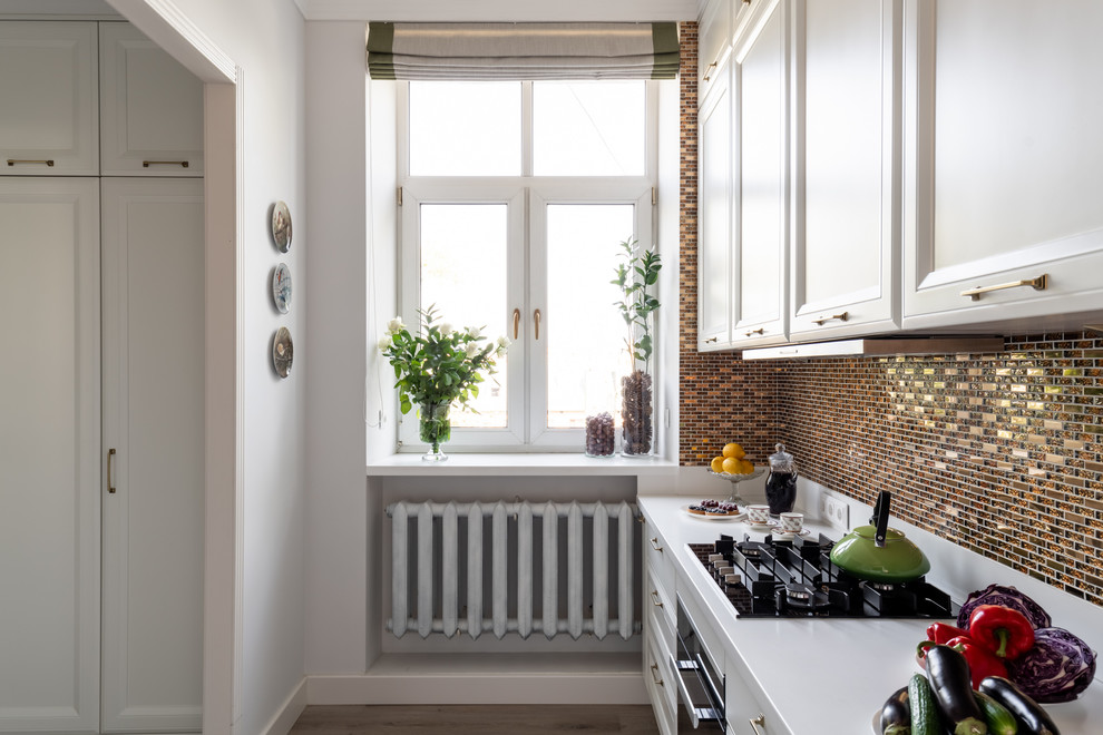 Mid-sized transitional l-shaped separate kitchen in Moscow with an undermount sink, raised-panel cabinets, white cabinets, solid surface benchtops, yellow splashback, mosaic tile splashback, stainless steel appliances, laminate floors, beige floor and white benchtop.