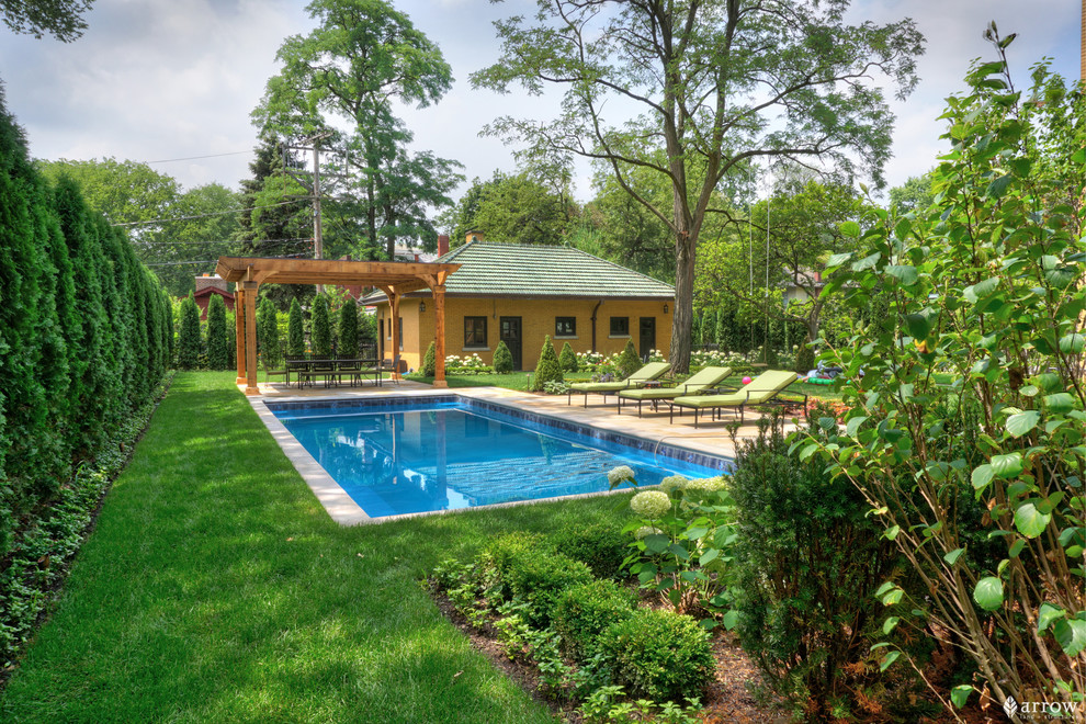 Mid-sized traditional backyard rectangular pool with a pool house and natural stone pavers.