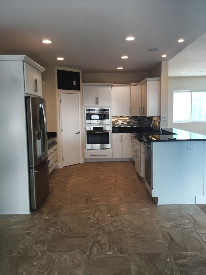 Inspiration for a mid-sized kitchen remodel with white cabinets, solid surface countertops, gray backsplash, stone tile backsplash and stainless steel appliances