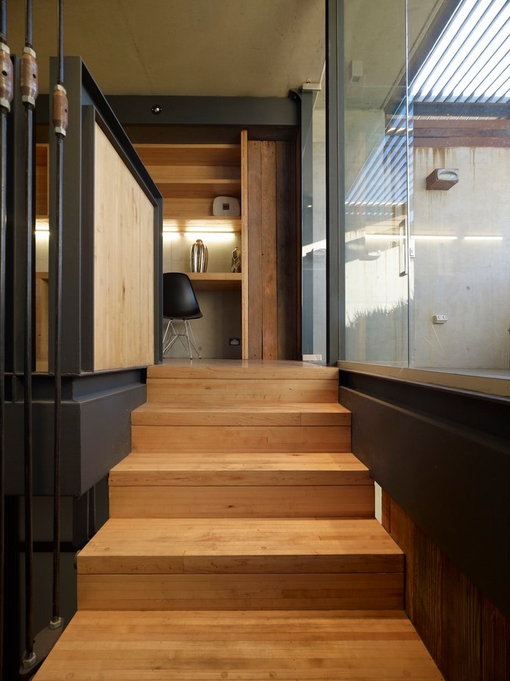 Industrial wood u-shaped staircase in Sydney with concrete risers and metal railing.