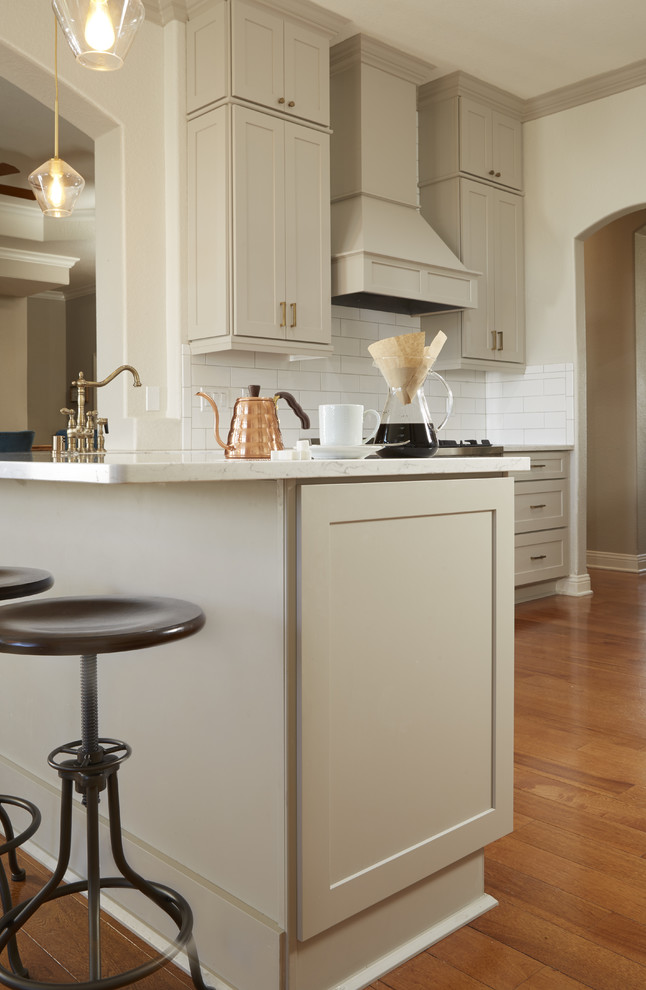 Example of a mid-sized transitional u-shaped medium tone wood floor and brown floor enclosed kitchen design in Atlanta with a farmhouse sink, shaker cabinets, gray cabinets, quartz countertops, white backsplash, subway tile backsplash, stainless steel appliances, a peninsula and white countertops