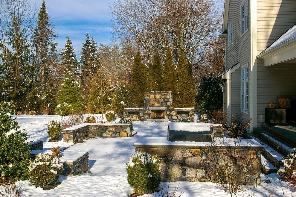 This is an example of a mid-sized traditional backyard patio in Boston with a fire feature and natural stone pavers.