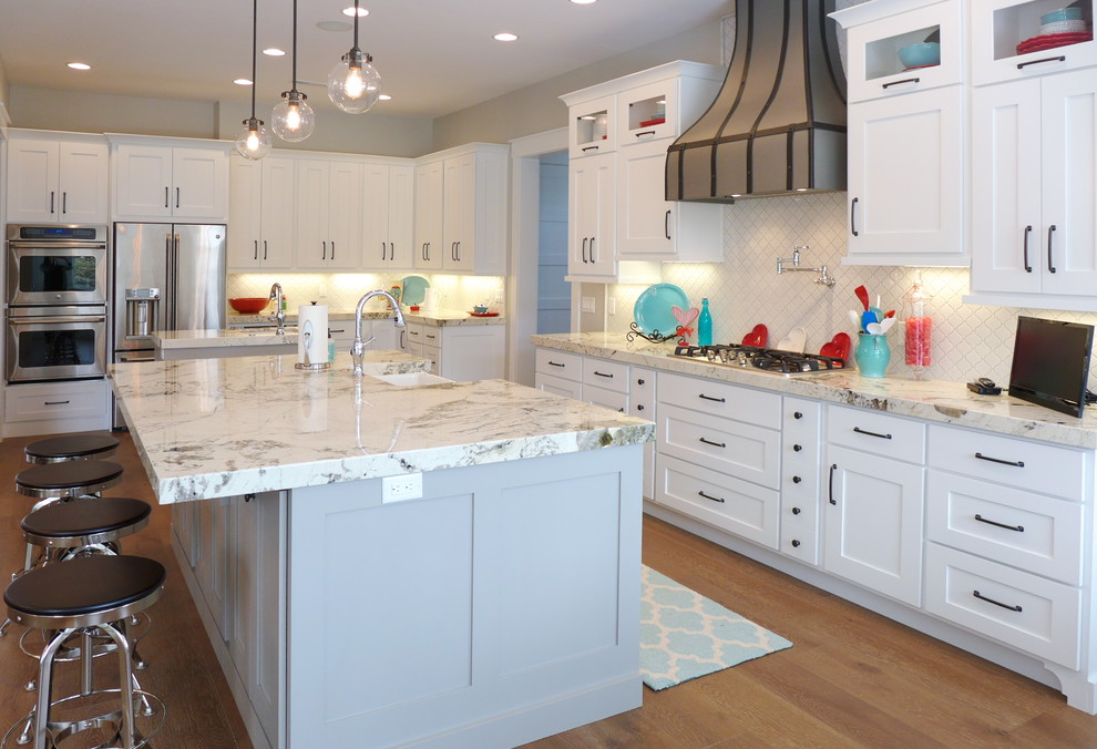 Inspiration for a mid-sized transitional galley open plan kitchen in Salt Lake City with a farmhouse sink, white cabinets, granite benchtops, white splashback, stainless steel appliances, multiple islands, shaker cabinets, subway tile splashback, medium hardwood floors and brown floor.