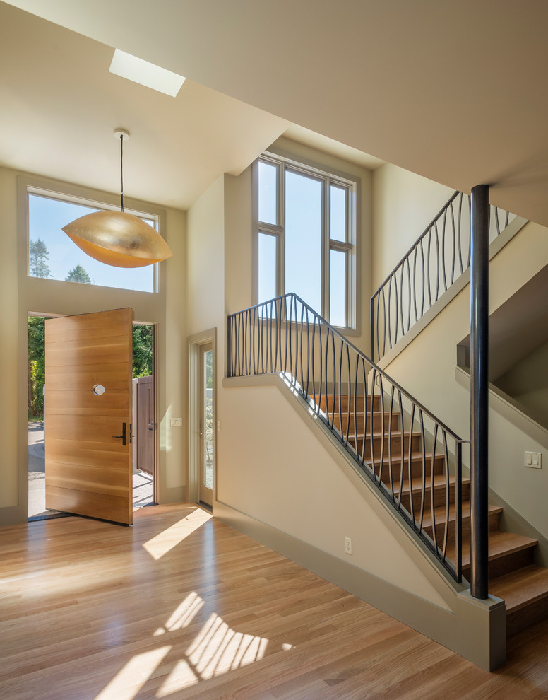 This is an example of a large contemporary foyer in Seattle with beige walls, light hardwood floors, a pivot front door, a light wood front door and beige floor.