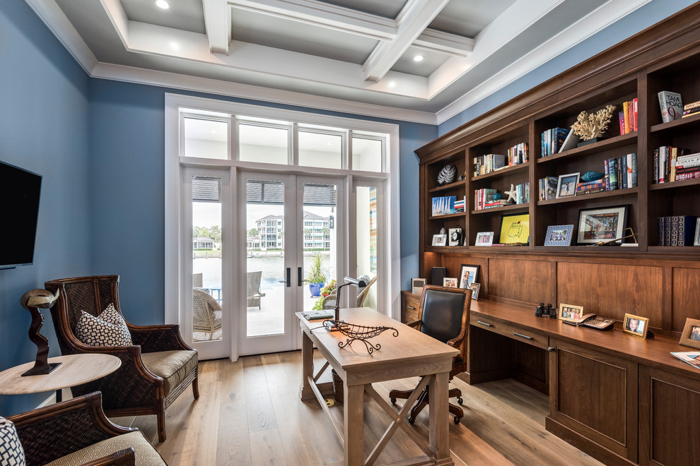 Photo of a transitional study room in Other with medium hardwood floors, blue walls, a freestanding desk and brown floor.
