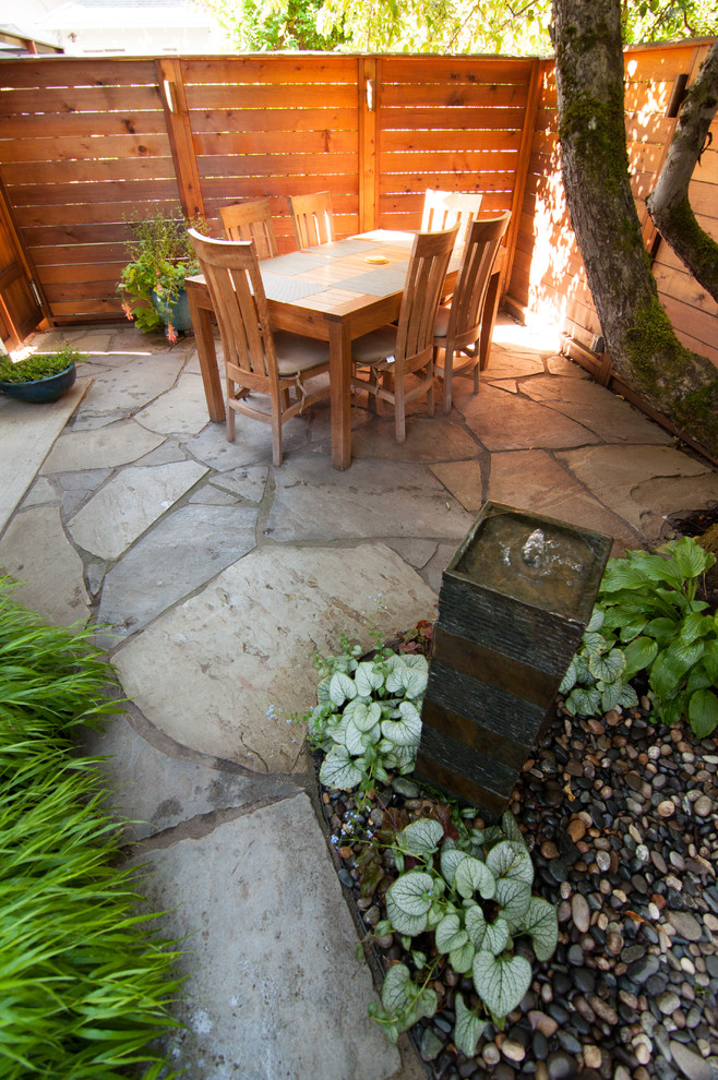 This is an example of a small asian backyard patio in Portland with natural stone pavers.