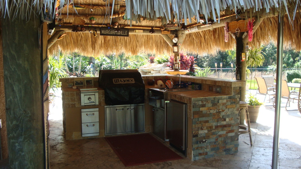 This is an example of a mid-sized tropical backyard patio in Miami with an outdoor kitchen and a gazebo/cabana.