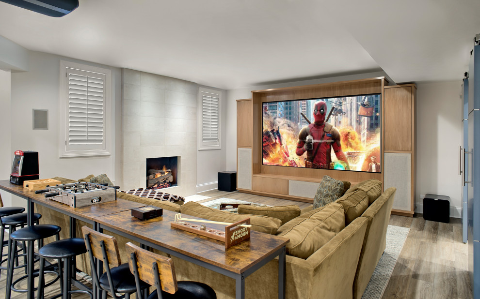 Modelo de cine en casa cerrado clásico renovado grande con paredes blancas, suelo de madera en tonos medios, pared multimedia y suelo gris