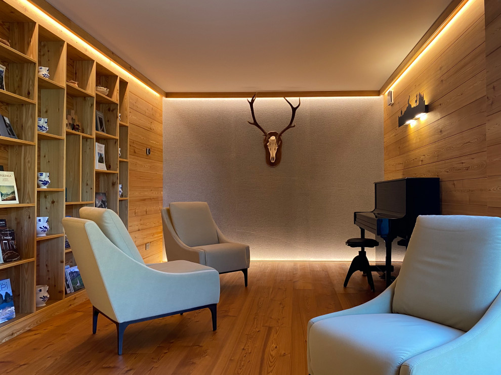 Bild på ett mellanstort minimalistiskt avskilt allrum, med ett bibliotek, mellanmörkt trägolv och en spiselkrans i sten