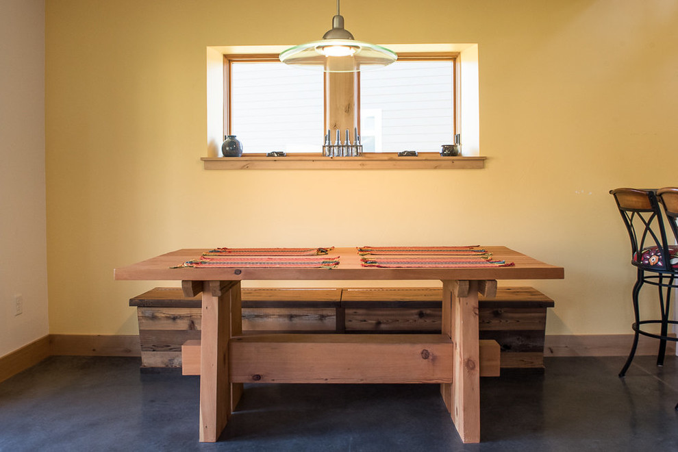 Example of a small mountain style concrete floor and gray floor kitchen/dining room combo design with yellow walls and no fireplace
