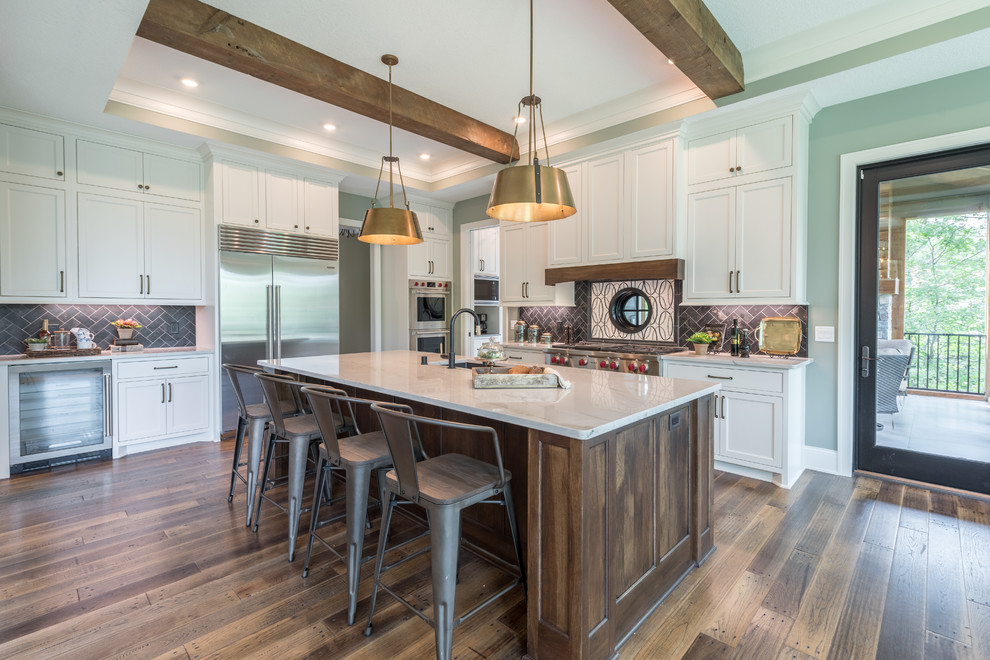 Design ideas for a transitional kitchen in Minneapolis with an undermount sink, shaker cabinets, white cabinets, black splashback, stainless steel appliances, dark hardwood floors, with island, brown floor and white benchtop.