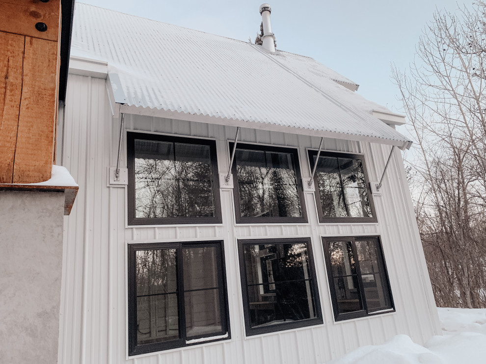 Idee per la villa piccola bianca country a due piani con rivestimento in metallo, tetto a capanna, copertura in metallo o lamiera e pannelli e listelle di legno