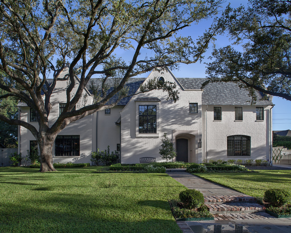 Inspiration for a large traditional two-storey brick beige house exterior in Houston with a gable roof and a shingle roof.
