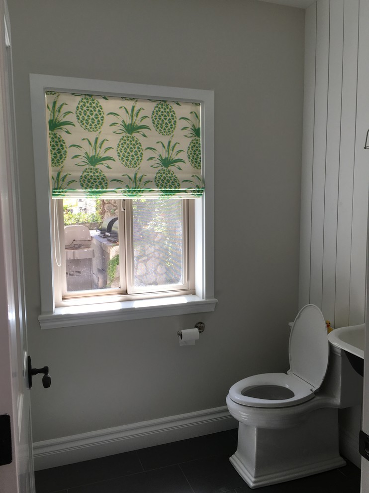Photo of a small country kids bathroom in Los Angeles with white cabinets, a two-piece toilet, grey walls, porcelain floors, a wall-mount sink and grey floor.