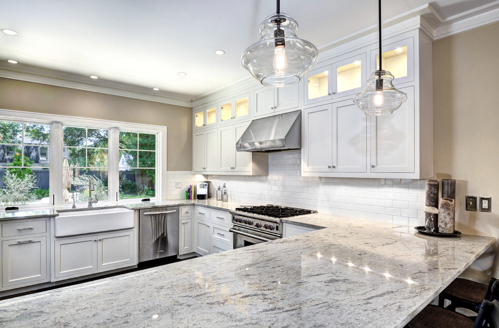 Eat-in kitchen - mid-sized transitional u-shaped eat-in kitchen idea in Charleston with a farmhouse sink, shaker cabinets, white cabinets, white backsplash, subway tile backsplash, stainless steel appliances and an island