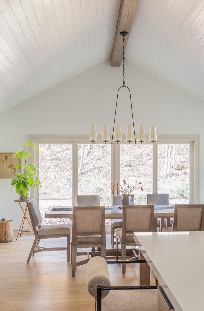 Ispirazione per una sala da pranzo aperta verso la cucina chic con pareti bianche, parquet chiaro, soffitto a volta e pavimento beige