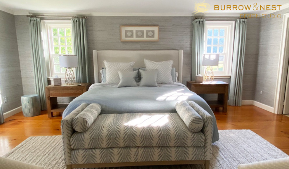 Large country master bedroom in Providence with blue walls, medium hardwood floors, a standard fireplace, a wood fireplace surround, brown floor and wallpaper.