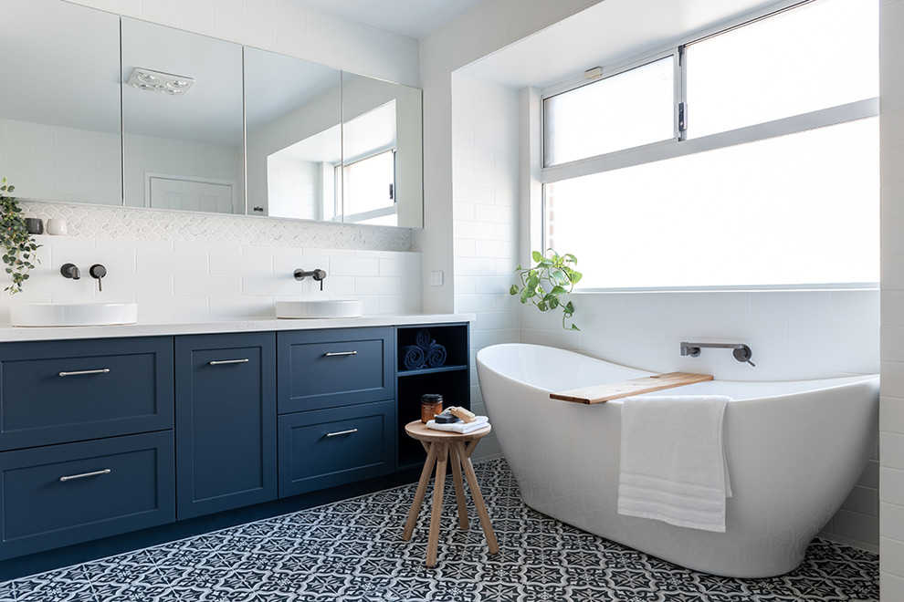 Design ideas for a master bathroom in Perth with blue cabinets, a freestanding tub, an open shower, white tile, ceramic tile, an open shower and white benchtops.