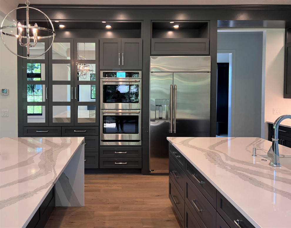 Kitchen - large transitional kitchen idea with an undermount sink, shaker cabinets, gray cabinets, quartz countertops, white backsplash, stainless steel appliances, two islands and white countertops