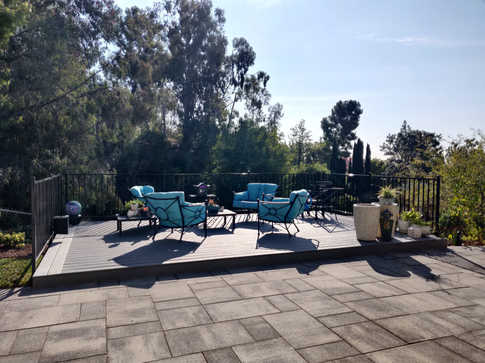 Large contemporary backyard and ground level deck in Orange County with no cover and metal railing.