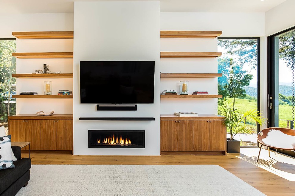 Design ideas for a contemporary open concept living room in San Francisco with white walls, medium hardwood floors, a standard fireplace, a plaster fireplace surround, a wall-mounted tv and brown floor.